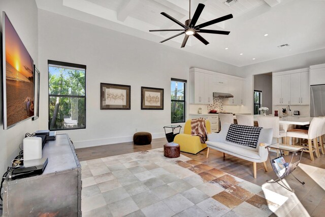 sitting room with a high ceiling, baseboards, beam ceiling, and recessed lighting