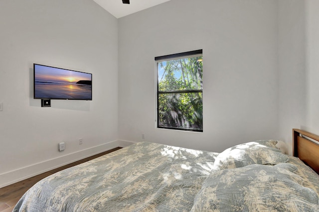 bedroom featuring baseboards, vaulted ceiling, and wood finished floors