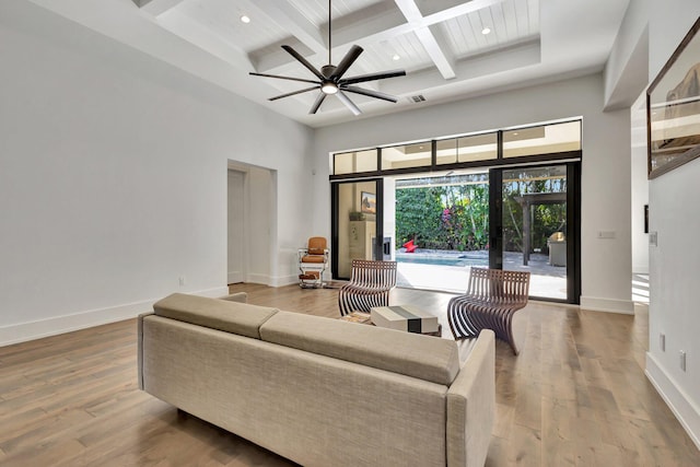 living room with wood finished floors, a towering ceiling, and baseboards