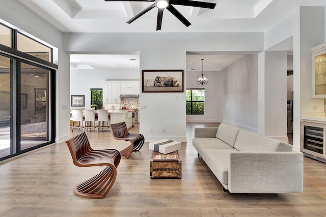 living room with wine cooler, baseboards, a raised ceiling, and wood finished floors