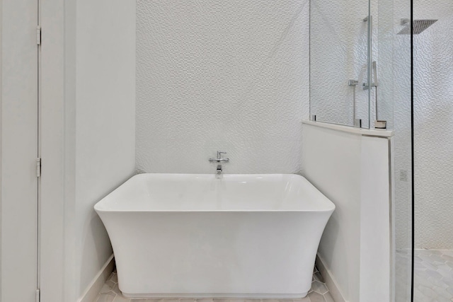 bathroom featuring a walk in shower, a soaking tub, baseboards, and tile patterned floors