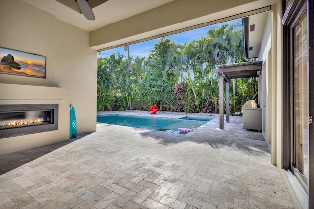 outdoor pool with a glass covered fireplace, a patio area, and ceiling fan