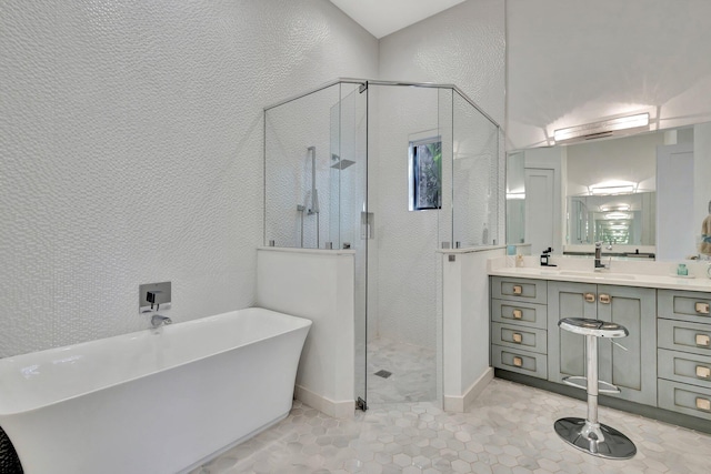 full bathroom featuring a textured wall, a freestanding bath, a shower stall, vanity, and tile patterned flooring