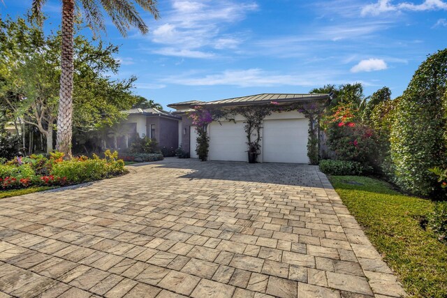 view of front of property featuring decorative driveway, a standing seam roof, metal roof, and an attached garage