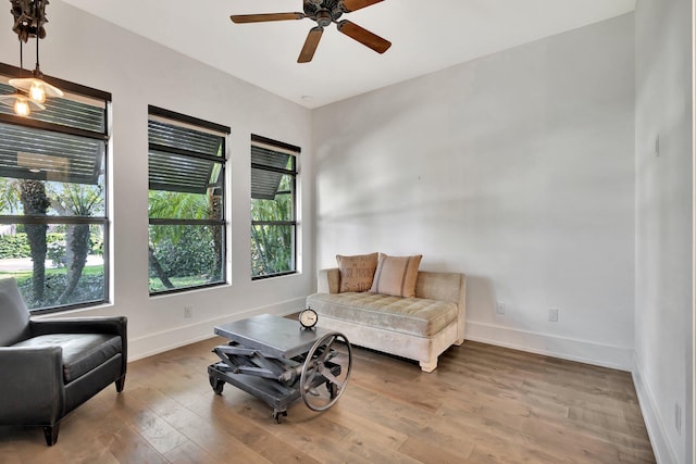 living area featuring ceiling fan, wood finished floors, and baseboards