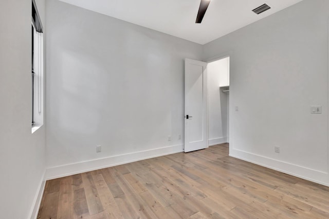 empty room with light wood finished floors, baseboards, visible vents, and ceiling fan