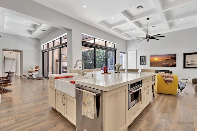 kitchen with stainless steel appliances, wood-type flooring, a towering ceiling, and cream cabinetry