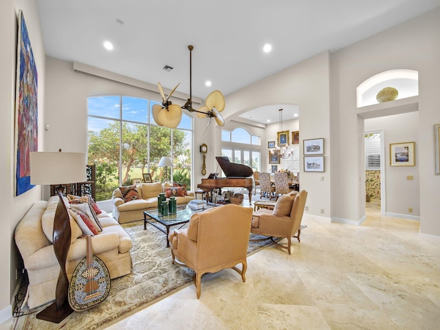 living area with baseboards, visible vents, an inviting chandelier, a high ceiling, and recessed lighting