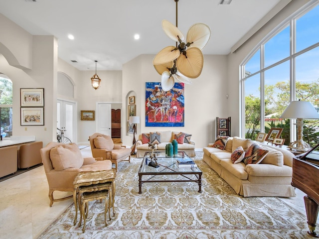 living area featuring visible vents, arched walkways, a ceiling fan, a towering ceiling, and recessed lighting