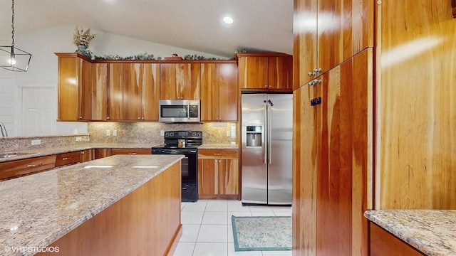 kitchen with appliances with stainless steel finishes, a sink, vaulted ceiling, and brown cabinetry