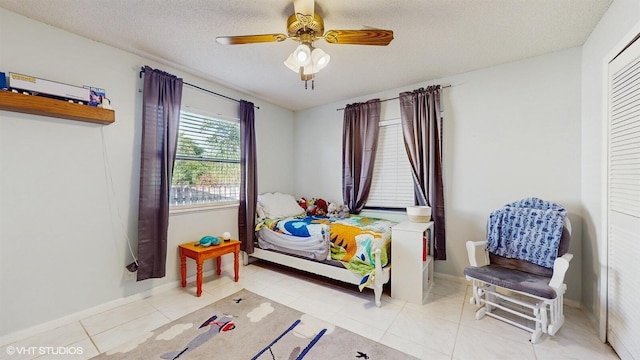 bedroom featuring tile patterned floors, baseboards, a ceiling fan, and a textured ceiling