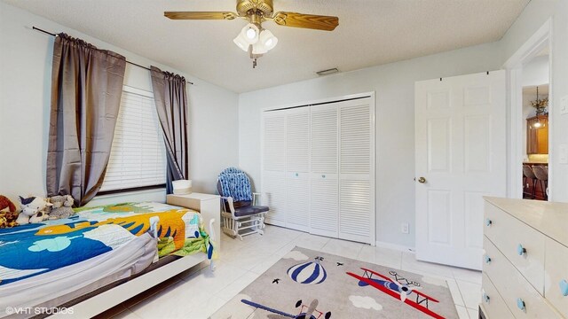 bedroom featuring a closet, light tile patterned floors, and a ceiling fan