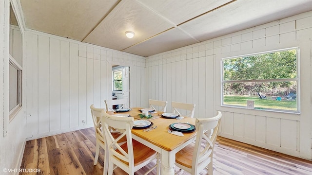 dining space featuring light wood-style flooring and wooden walls