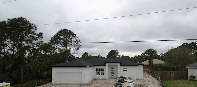 view of front of house with an attached garage, fence, and stucco siding