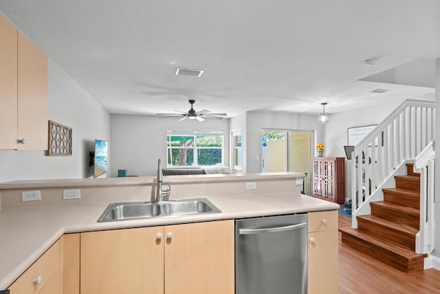 kitchen featuring a sink, visible vents, light countertops, stainless steel dishwasher, and light brown cabinetry