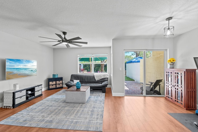 living room featuring a textured ceiling, wood finished floors, a ceiling fan, and baseboards