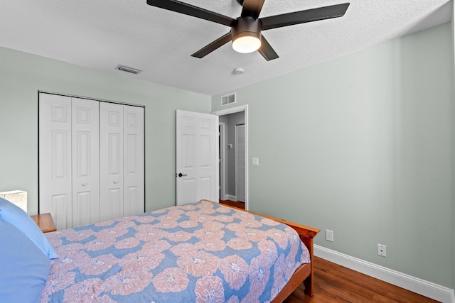 bedroom featuring baseboards, a closet, visible vents, and wood finished floors