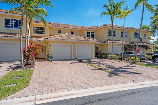 view of front of property featuring decorative driveway, a tiled roof, an attached garage, and stucco siding