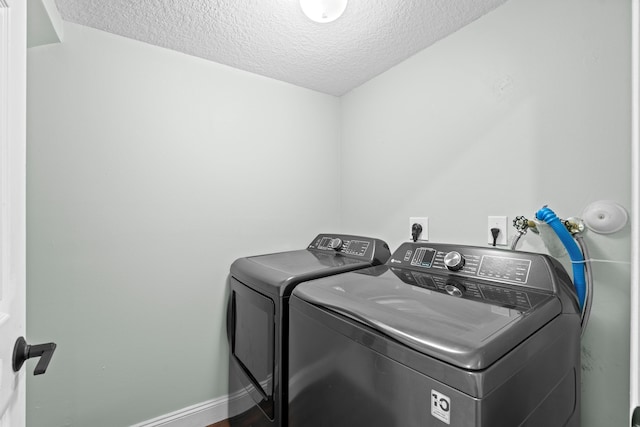 laundry area with laundry area, independent washer and dryer, a textured ceiling, and baseboards