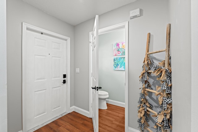 bathroom with wood finished floors, toilet, and baseboards