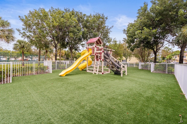 communal playground featuring a lawn and fence