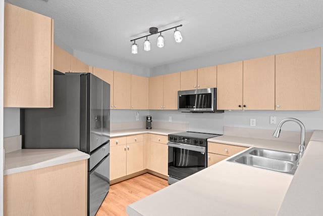 kitchen with a sink, stainless steel appliances, light wood-type flooring, and light brown cabinets