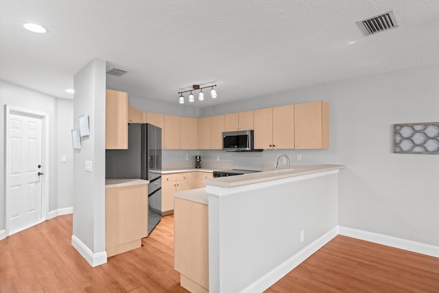 kitchen featuring visible vents, light brown cabinets, stainless steel microwave, and light countertops