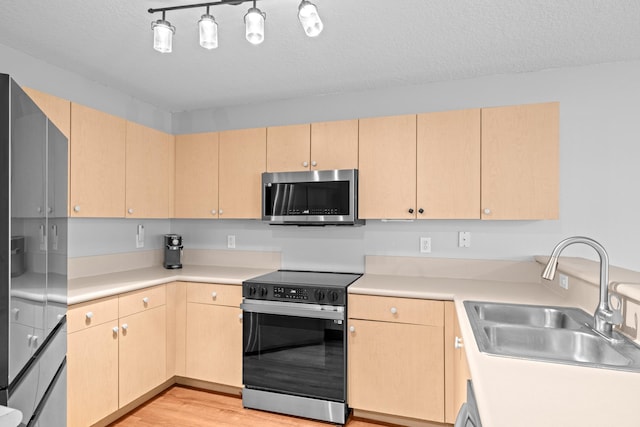 kitchen featuring light brown cabinets, electric range, stainless steel microwave, and a sink