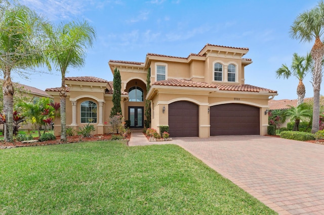 mediterranean / spanish-style house featuring a tiled roof, french doors, decorative driveway, stucco siding, and a front lawn