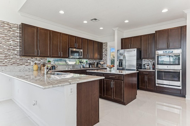 kitchen with dark brown cabinetry, a peninsula, stainless steel appliances, crown molding, and a sink