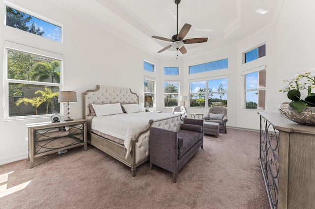 bedroom featuring a tray ceiling, crown molding, light colored carpet, a towering ceiling, and baseboards