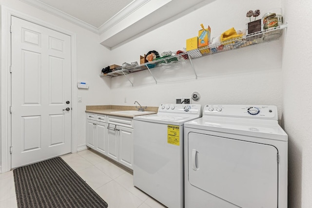 laundry area featuring crown molding, washing machine and clothes dryer, cabinet space, light tile patterned flooring, and a sink