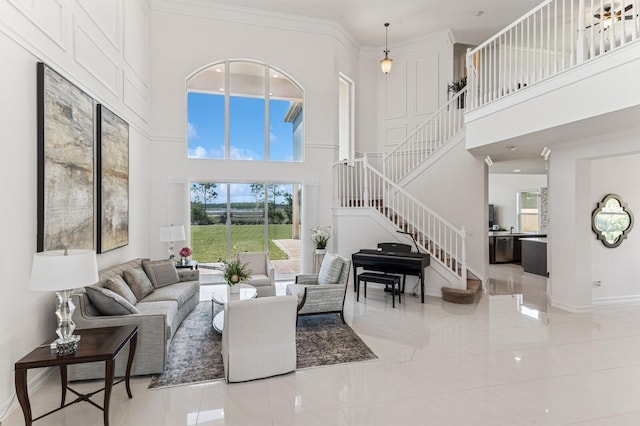 living area with a towering ceiling, baseboards, stairway, and crown molding