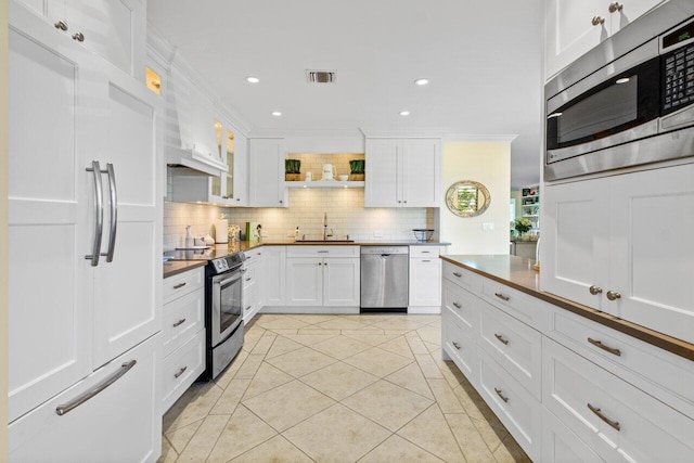 kitchen with visible vents, decorative backsplash, ornamental molding, a sink, and built in appliances