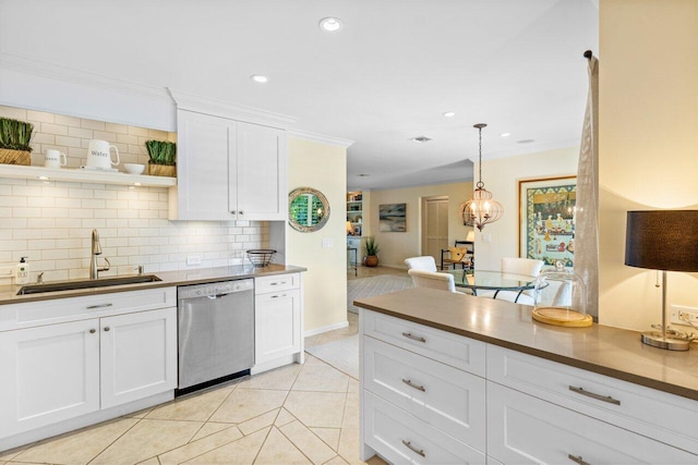 kitchen with backsplash, crown molding, stainless steel dishwasher, white cabinetry, and a sink