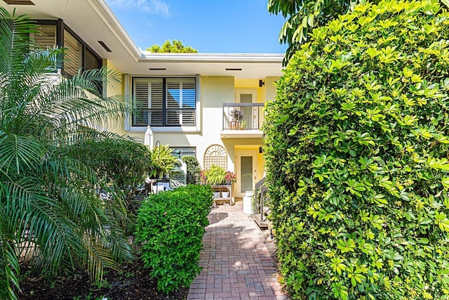 view of exterior entry featuring a balcony and stucco siding