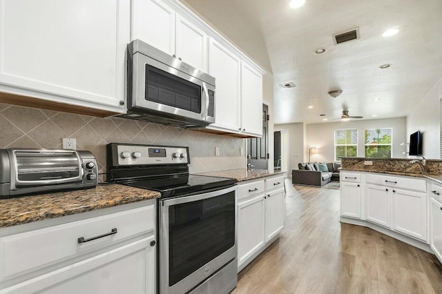 kitchen featuring light wood-type flooring, visible vents, tasteful backsplash, white cabinetry, and stainless steel appliances