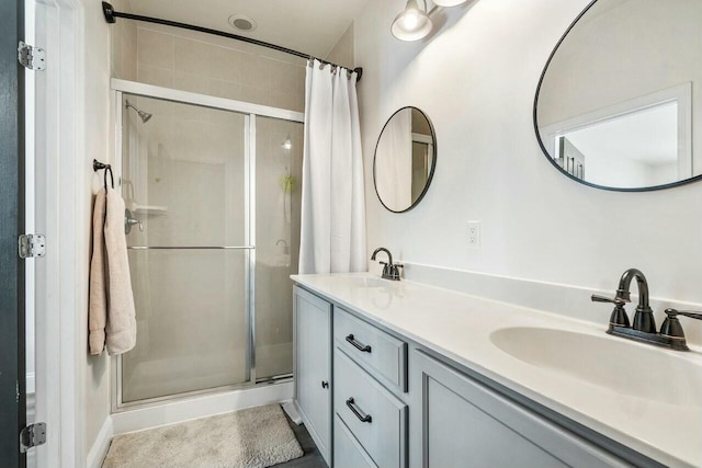 bathroom with double vanity, a stall shower, and a sink