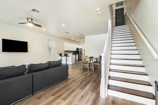 living room with recessed lighting, visible vents, light wood-style flooring, and stairway