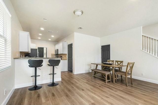 kitchen featuring a breakfast bar, light wood-style flooring, visible vents, and white cabinets