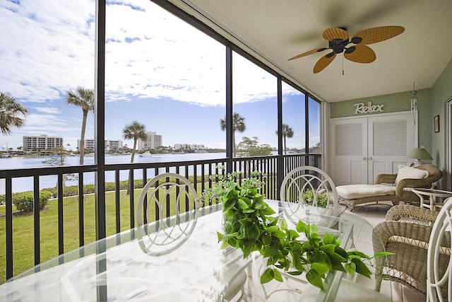 sunroom featuring a ceiling fan and a water view