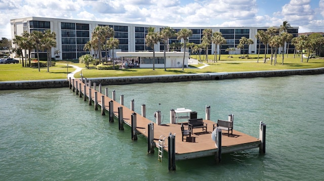 view of dock with a lawn and a water view