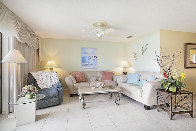 living area featuring light tile patterned floors, ceiling fan, visible vents, and a textured ceiling