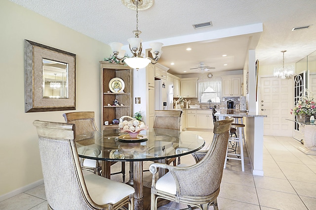 dining space featuring a textured ceiling, light tile patterned flooring, visible vents, baseboards, and an inviting chandelier