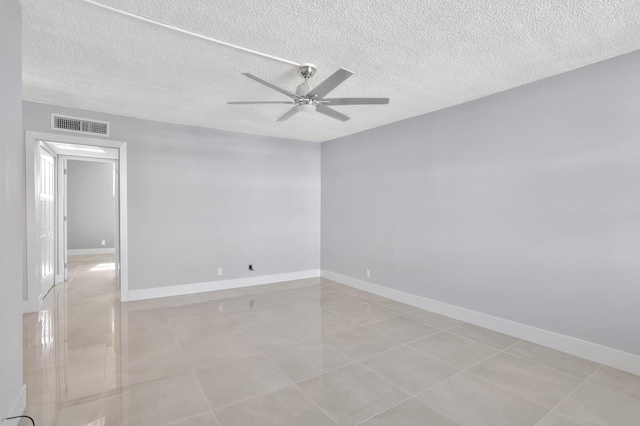 spare room with a ceiling fan, visible vents, a textured ceiling, and baseboards