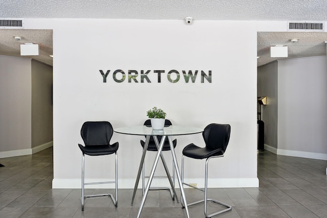 tiled dining room featuring visible vents, a textured ceiling, and baseboards