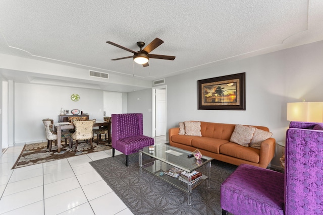 living room featuring a ceiling fan, visible vents, a textured ceiling, and light tile patterned flooring