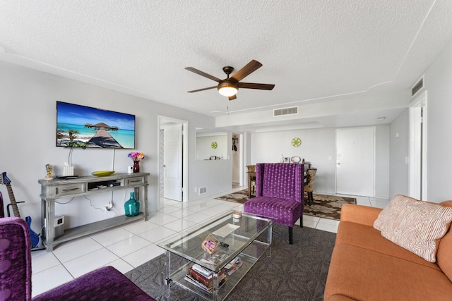 living area with tile patterned flooring, visible vents, ceiling fan, and a textured ceiling