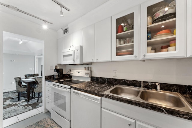 kitchen featuring white appliances, dark countertops, a sink, and white cabinets