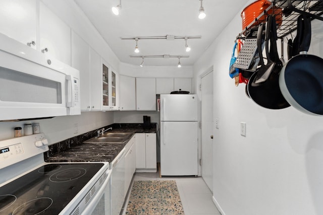 kitchen featuring dark countertops, white appliances, white cabinetry, and a sink